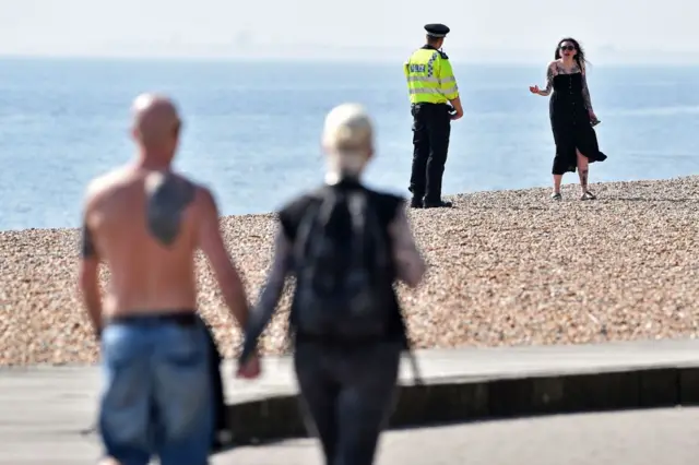 Police officer talks to a woman on a beach in Brighton