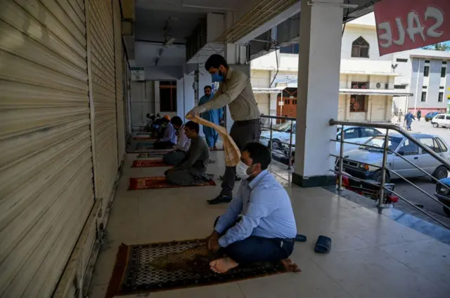 A few worshippers arrive to offer Friday prayers outside a closed mosque during a government-imposed nationwide lockdown as a preventive measure against the COVID-19 coronavirus, in Islamabad