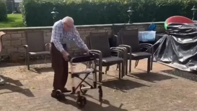 Mr Moore uses a walking frame to help him on his laps of the garden