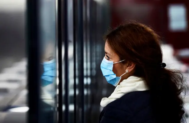 A woman wearing a face mask enters a subway station in Barcelona