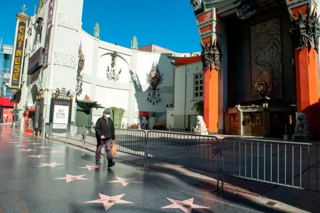 A person wearing a mask walks past the TCL Chinese Theater in Hollywood