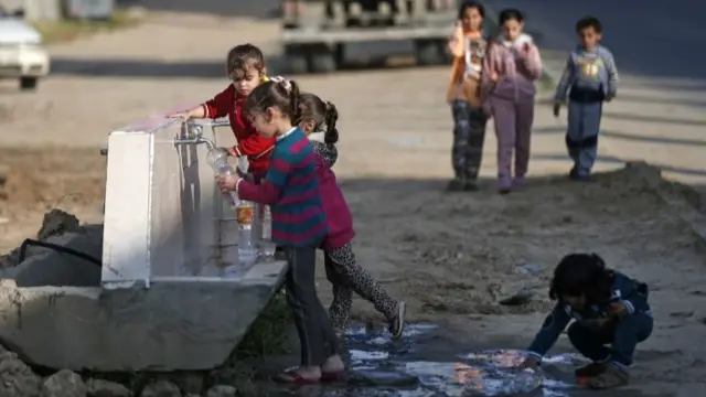 Palestinian children fill plastic bottles with water at a refugee camp in Khan Younis in the southern Gaza Strip on 11 April 2020