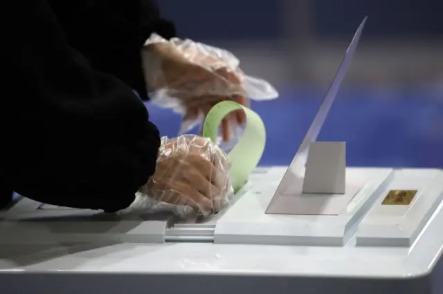 A South Korean woman wears plastic gloves cast her vote in a polling station