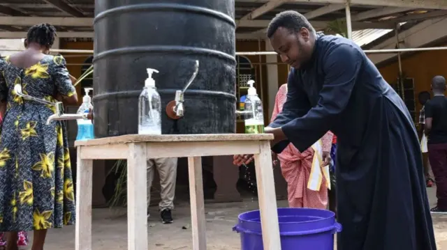 Catholic Priest washes his hands after leading Palm Sunday mass in Arusha, Tanzania