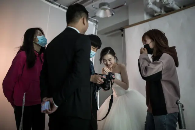 The wedding photographer and assistant take photos for a couple