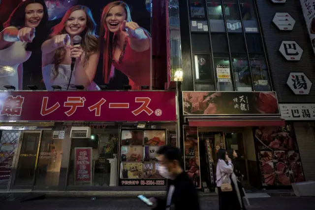 Pedestrians walk past a closed karaoke store in the Kabukicho entertainment area on April 11, 2020 in Tokyo, Japan.