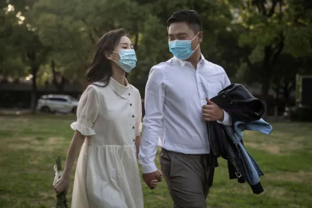 A couple wearing masks pose for wedding photos at the Jiangtan park on April 15, 2020 in Wuhan, central China's Hubei Province