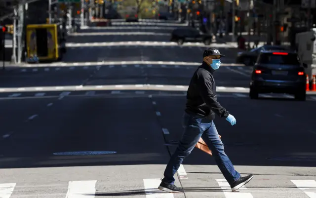 Man wearing a face mask crosses New York's 6th Avenue