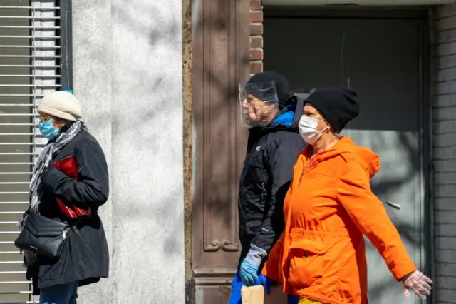 People wearing masks walk through New York City