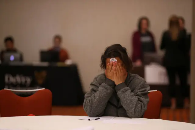 A job seeker pauses while filling out an application at the HireLive career fair