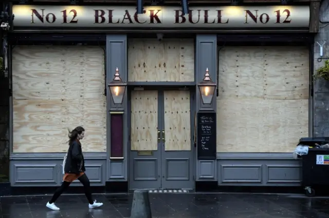 A woman walks past a closed pub in Edinburgh's Grassmarket