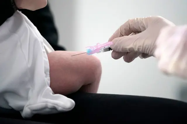 A medical worker delivers an injection to a baby