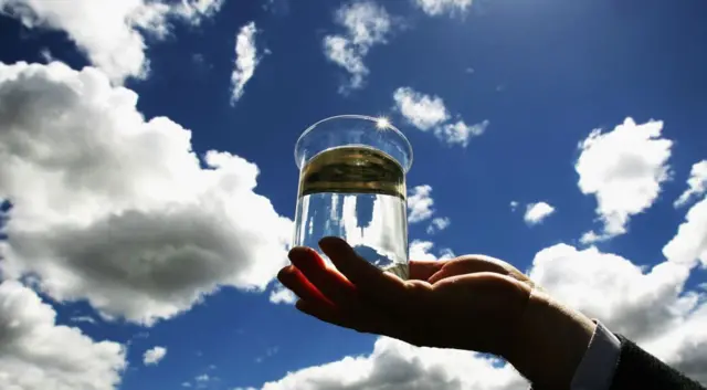 Man holds up beaker of recycled sewage water