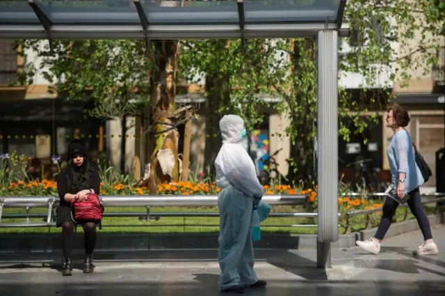 An employee waits for the arrival of a public bus to clean it as a preventive measure against the spread of the COVID-19 coronavirus in the Spanish Basque city of San Sebastian