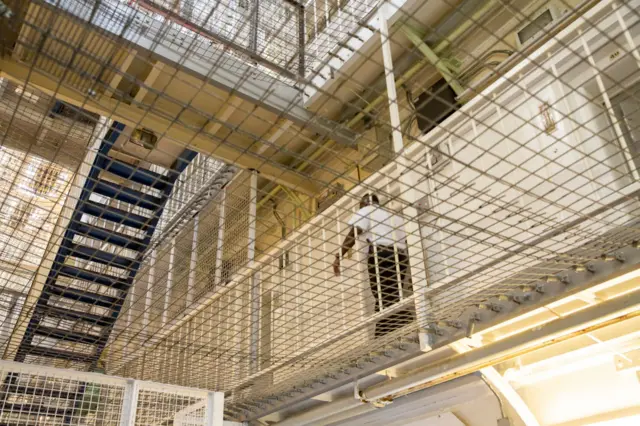 A Prison Officer walks along the landing of HMP Pentonville, London