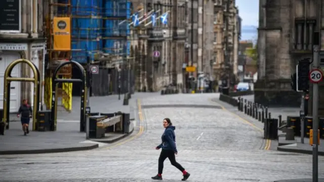 A woman walks up an empty Royal Mile in Edinburgh