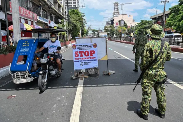 Policemen wearing face shields inspect motorists at a quarantine checkpoint in the Philippines