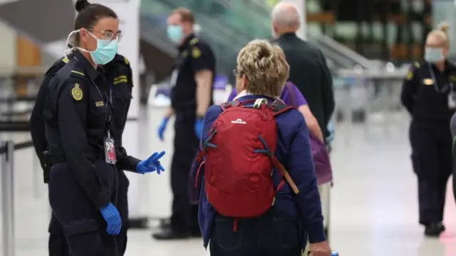 An Australian immigration officer talking to a New Zealand passenger transiting through Australia