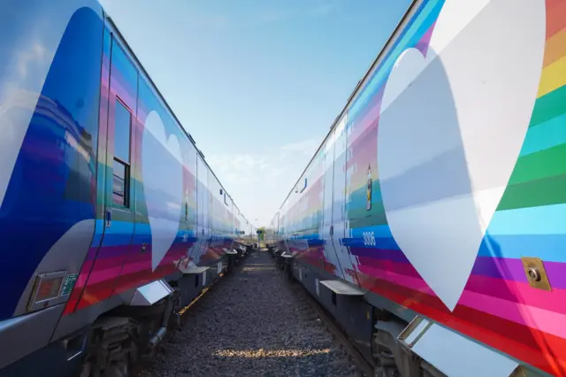 Two trains painted in rainbow colours