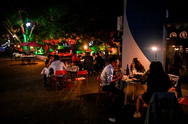 People eat outside at restaurants in Wuhan, China, on Thursday