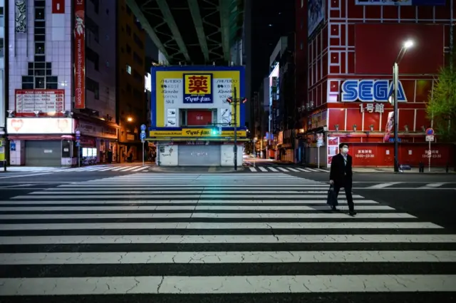 A man in a mask walks around the deserted Akihabara area of Tokyo on 17 April