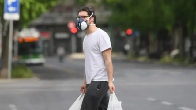 A man wearing a face mask carries bags, amid the coronavirus disease (COVID-19) outbreak, in Milan,