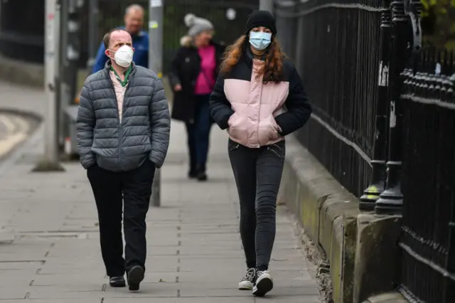 Two people wear masks walking in Edinburgh