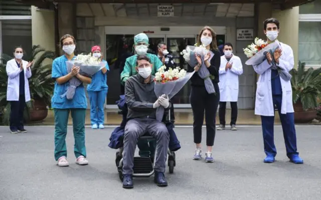 People outside a hospital with flowers