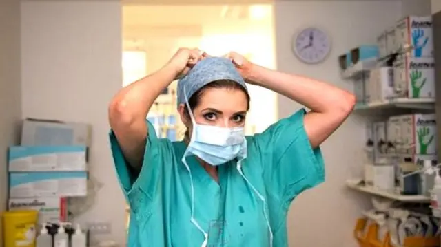 A nurse puts on protective clothing