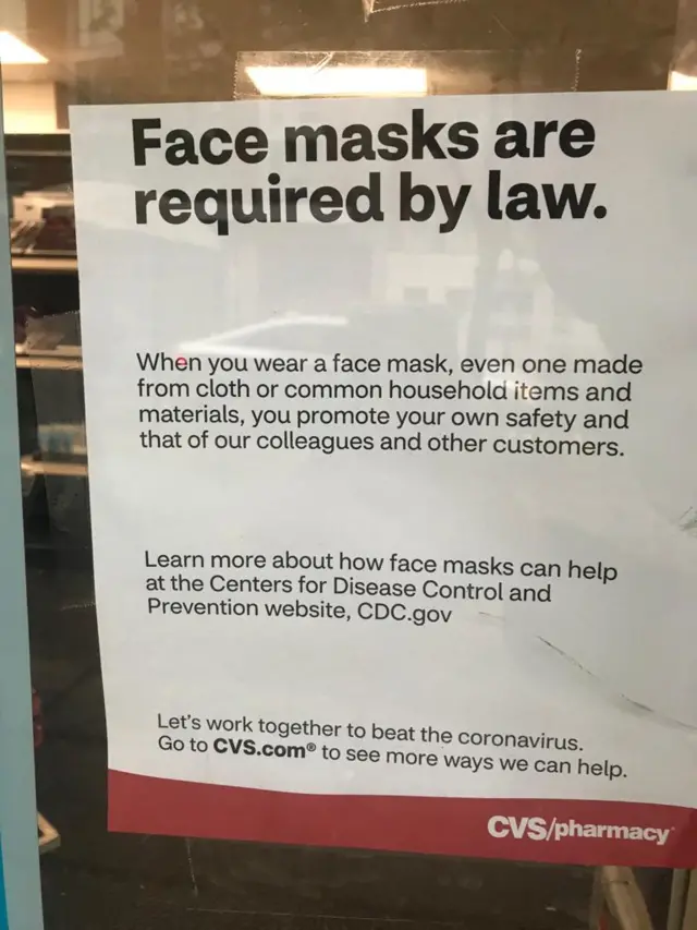 A sign outside a pharmacy reads: "Face masks are required by law"