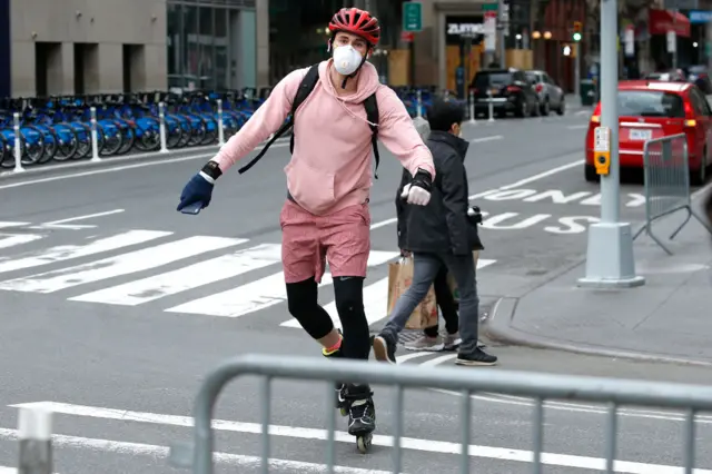 A man rollerblades across the street in while wearing a protective mask during the coronavirus pandemic on 18 April, 2020 in New York City