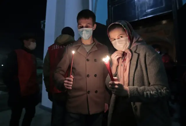 Worshippers in masks hold lit candles to celebrate Easter in Moscow, Russia