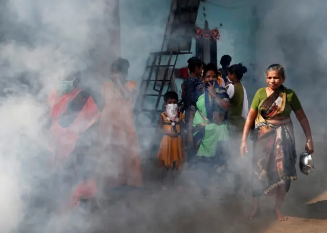 Women and children cover their faces from a fumigation drive in Mumbai (Bombay), India