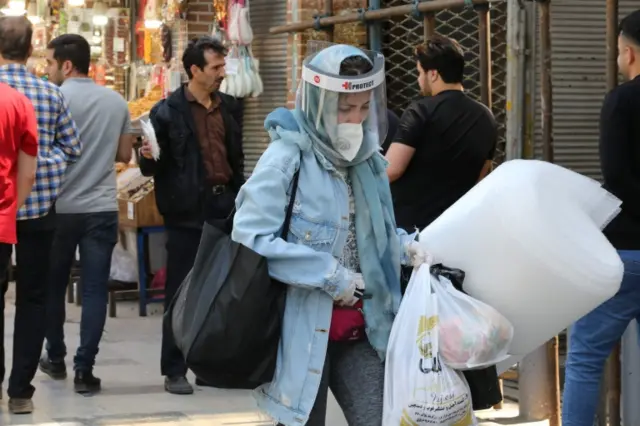 An Iranian woman wearing protective gear shops at the Grand Bazaar market in the capital Tehran