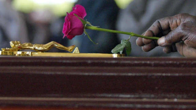 A person placing a rose on a casket in Kenya - archive shot