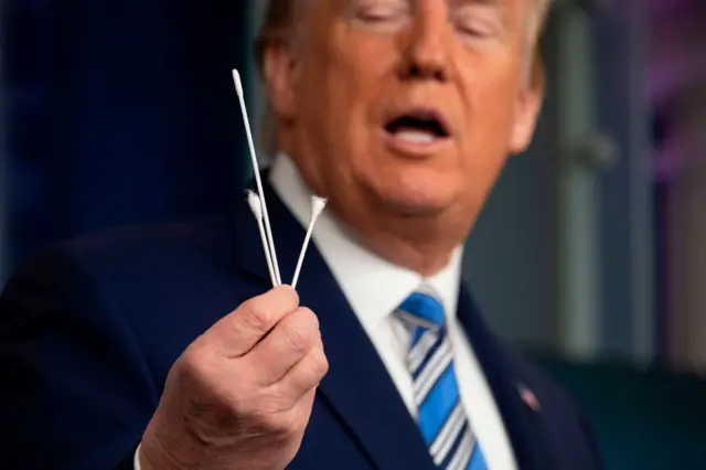 US President Donald Trump holds up swabs as he speaks during a Coronavirus Task Force press briefing at the White House in Washington, DC, on April 19, 2020