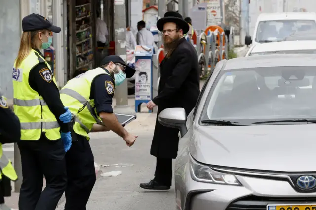 Israeli police talk to a driver at a checkpoint in Bnei Brak, near Tel Aviv with a largely ultra-Orthodox population, on 31 March 2020