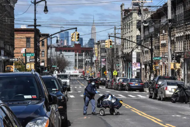 A postal worker delivers mail to a deserted Brooklyn street