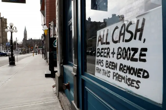 A sign in a closed restaurant window in Ottawa, Canada reads "All cash, beer and booze has been removed from the premises"