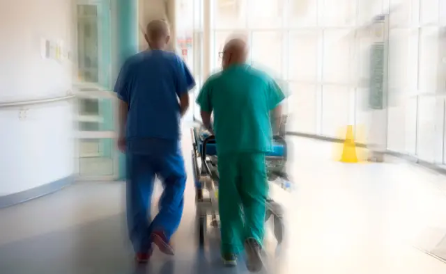 Hospital staff push a patient through hospital