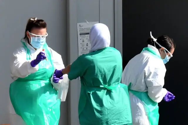 Medical staff wear PPE as they prepare to store test samples