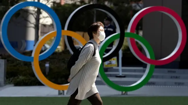 Woman walking in from of Olympic rings