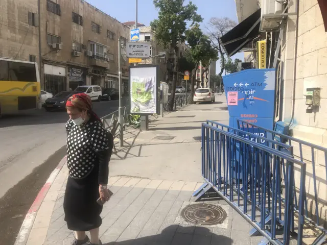 Woman with mask walking at entrance to Mea Shearim