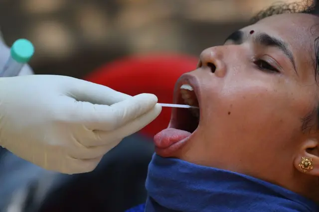 A doctor takes a swab sample of a resident at a Covid-19 coronavirus testing drive inside the Dharavi slums