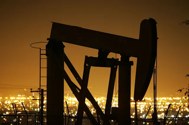 Pumps draw petroleum from oil wells through the night in California.