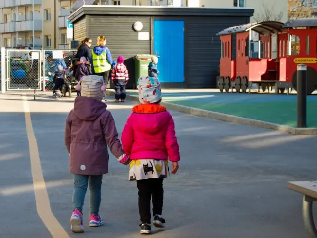 Two Norwegian children hold hands as they enter their kindergarten on the day they reopen