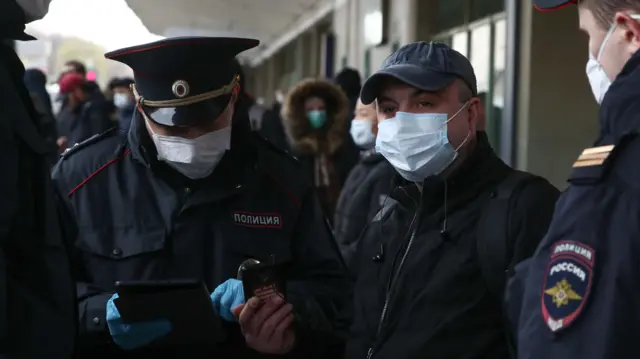 Police officers check a digital pass code for travel across Moscow