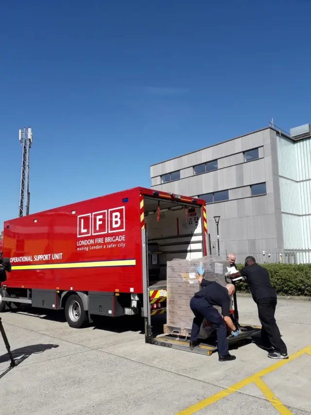 Firefighters loading personal protective equipment onto a lorry