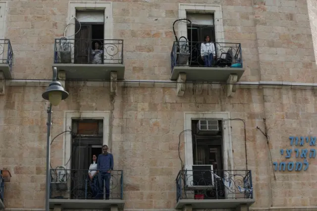 Israelis stand on their balconies in silence to mark Holocaust Remembrance Day in Jerusalem on 21 April 2020