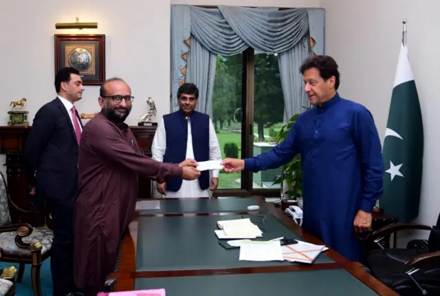 Pakistani Prime Minister Imran Khan (right) receives a cheque from Head of the Edhi Foundation Faisal Edhi, for the Prime Minister"s coronavirus disease (COVID-19) relief fund at the Prime Minister House in Islamabad, Pakistan April 15, 2020.